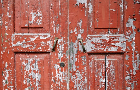 Close-up of weathered texture and peeling red paintwork of an old wooden door の写真素材