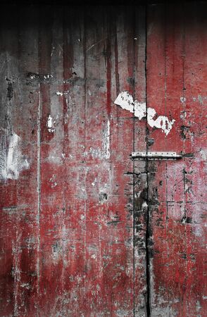 Old weathered, wooden door with lock  Painted dark red with a textured and faded surface の写真素材