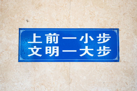 Chinese male lavatory sign stating \"A small step forward is a large step towards civilization.\"の写真素材