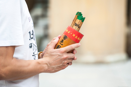 WONG TAI SIN, HONG KONG - OCT 27, 2013 - Man holds a box of fortune sticks at Wong Tai Sin temple, Hong Kongのeditorial素材