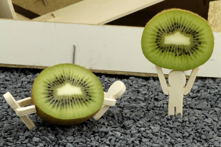 Three wooden figures present slices of kiwiの写真素材