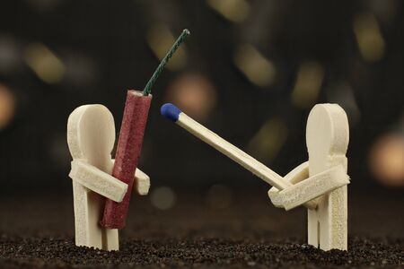 One small wooden male holds a banger and the other one holds a matchstickの写真素材