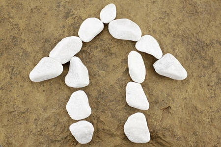 Small house of white pebbles in front of brown stoneの写真素材