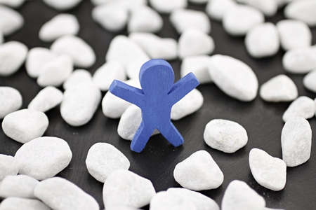 A blue male stands alone in a group of white pebblesの写真素材