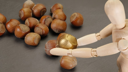 Hazelnuts and wooden mannequin on a black background.