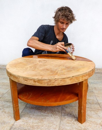 Young man painting old table so it looks like a new oneの写真素材