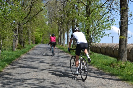 Spring bike riding through tree avenue, Young couple on bikes riding through tree avenue during beautiful spring dayの写真素材