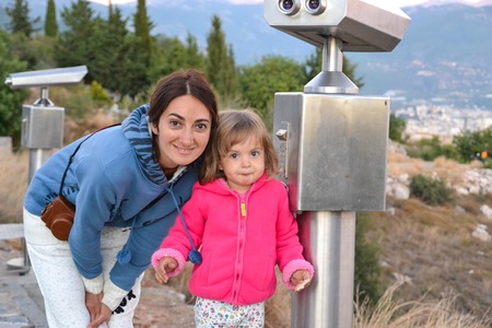 Mom and her little daughter on the trip on the view point with binoculars in Alanyaの写真素材