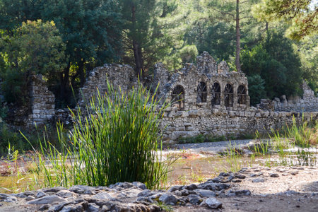 Ancient Stone Ruins with Arched Windows in the Forested Landscape of Olympos, Turkey, Near a Peaceful Riverの写真素材