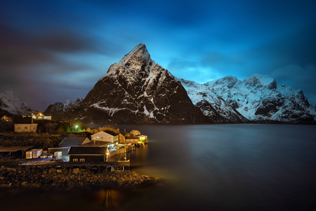 Fishing factory working nightly in Reine with fjord and mountains in background, Lofotenの写真素材