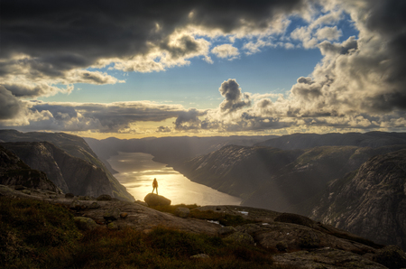 Woman hiking at sunset on Kjerag cliff over Lysefjorden, Norwayの写真素材
