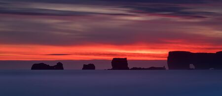 Rocks of Dyrholaey peninsula in colorful sunset, Icelandの写真素材