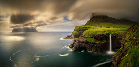 Panorama of Gasadalur village and cloudy Mykines island in sunset, Faroe Islandsの写真素材