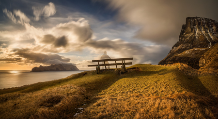 Bench at Gasadalur village and Mykines Island in sunset, Faroe Islandsの写真素材