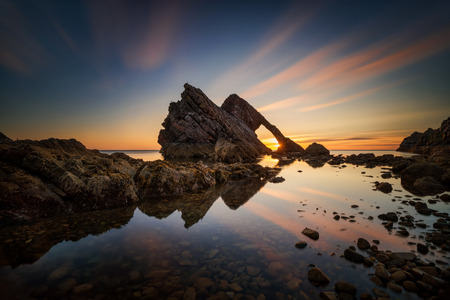 Bow Fiddle Rock reflection in sunrise light, Portknockie, Scotlandの写真素材