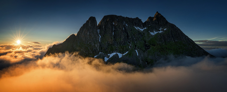 Breidtinden summit over cloudy Mefjorden in sunset light, Senja, Norway