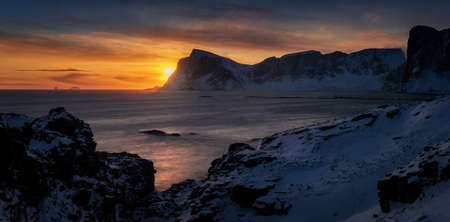 Panorama of Mahornet summit and Vaeroy ridge at orange sunset, Lofoten Norway