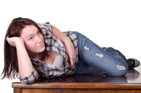A photograph of a girl isolated lying on a wood dest day dreaming about the future.の写真素材