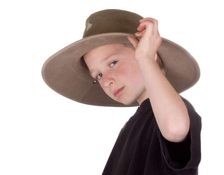 A photograph of a young boy tippinh his hat with a small grin on his face.の写真素材