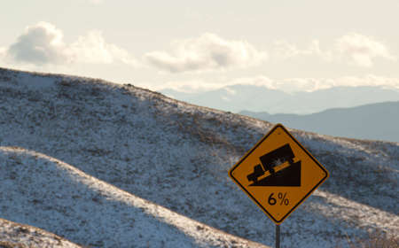 A six percent grade sign with some mountains in the background.の写真素材