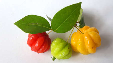 Malang, Indonesia - Dec 21,  2019 : three red, green and yellow suriname cherries with green leaves