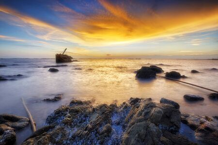 Natural seascape view with wreck ship at sunsetの写真素材