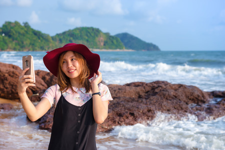 Young Asia woman taking photo of herself in her travel at the beach, travel conceptの写真素材