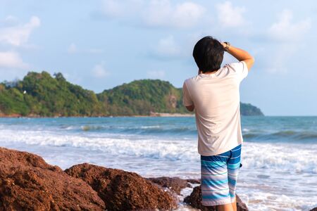 Rear view of young photographer taking view of seaの写真素材