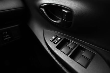 Car interior details of door handle with windows controls and adjustments. Car window controls and detailsの写真素材
