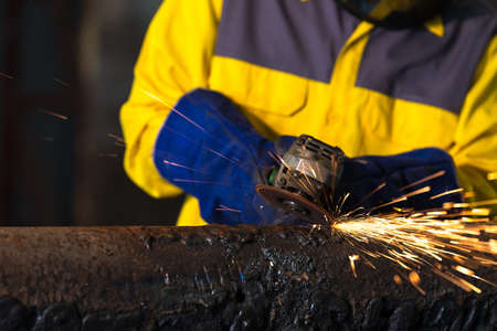 Electric wheel grinding on steel structure in factory