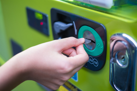 Hand inserting coins into vending machineの写真素材