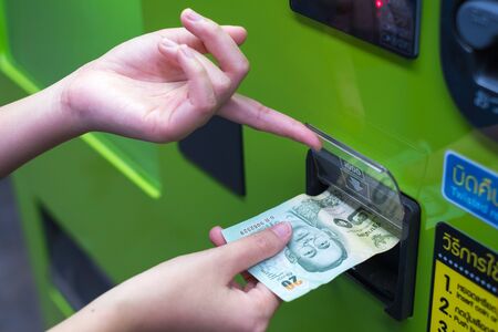 Hand inserting cash into a vending machineの写真素材