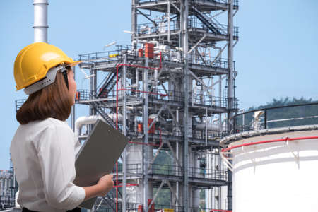 Female engineer wearing safety helmet inspects pipeline industry siteの写真素材
