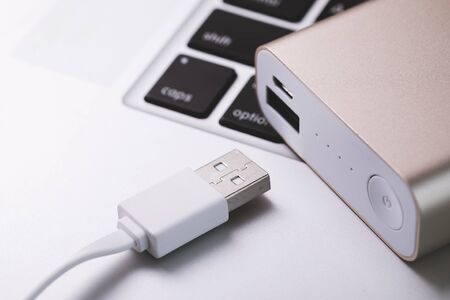 Pink power bank, portable battery charger on laptop