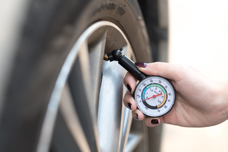 Hand holding portable pressure gauge for car tyre pressure measurementの写真素材