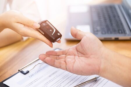 Car loan, contract agreement,buying and rent car concept, Saleperson holding car key on handの写真素材
