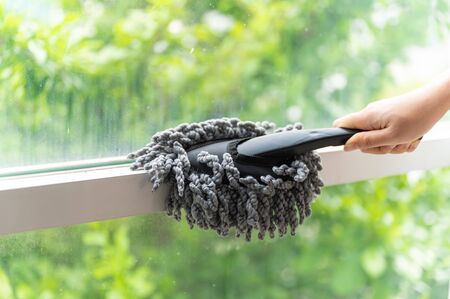 Close up young Asian woman holding dust wiper cleaning house windowの写真素材