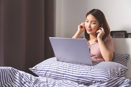 Young asian chinese ethnicity using laptop browsing,working,meeting or online learning at homeの写真素材