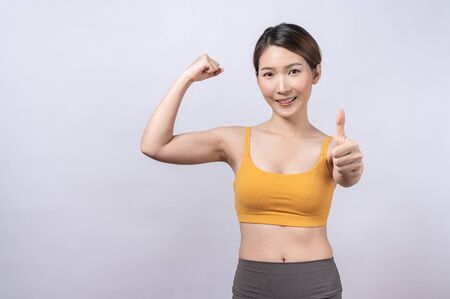 Portrait of Asian sporty woman giving thumb up isolated on white background. concept of healthy lifestyleの写真素材
