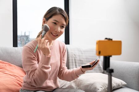 Asian woman blogger live steam video of makeup cosmetic at home online influencer on social media conceptの写真素材