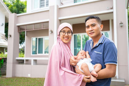 Portrait of young adult parent holding newborn baby infront home. concept of new life and familyの写真素材