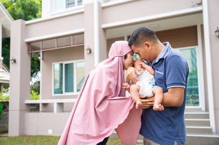Portrait of young adult parent holding newborn baby infront home. concept of new life and familyの写真素材