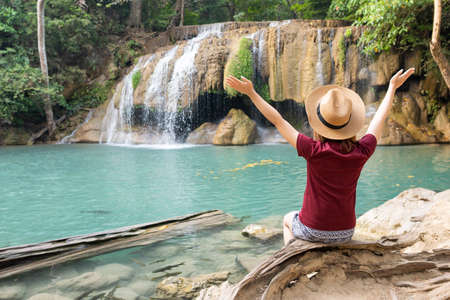 Rear view of young woman traveling in Erawan waterfall in Kanchanaburi Thailandの写真素材