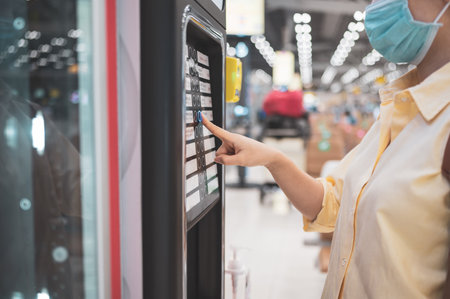 Asian woman buying can drink from vending machine in airport