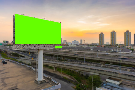 Large blank billboard pole beside highway in city at dusk background with green screenの写真素材