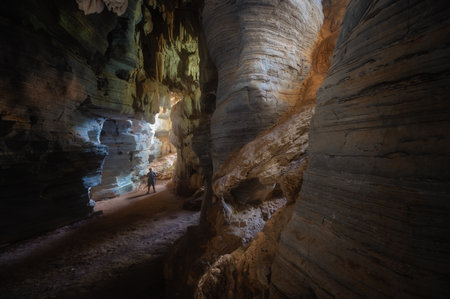 Man exploring the cave in Tam See Fah or Blue cave in Tak province, Thailandの写真素材