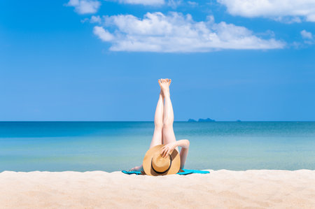 Rear view of  woman wearing sun hat and white bikini spends vacation at the beach on a white sand. summer beach conceptの写真素材