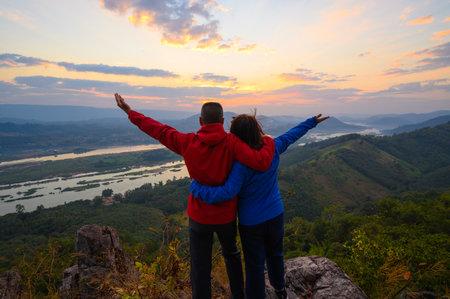 Senior healthy couple hiked the hill to see the sunrise view over Mekong river at Phu Pha Dak hill in Nong Khai, Thailandの写真素材