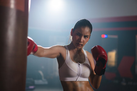 Young Asian doing boxing or Muay Thai punching sandbag in fitness club or gym. healthcare and sport concept.の写真素材
