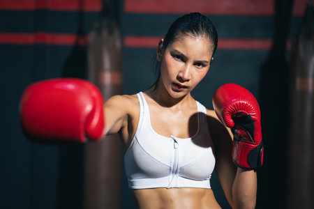 Young Asian doing boxing or Muay Thai punching sandbag in fitness club or gym. healthcare and sport concept.の写真素材